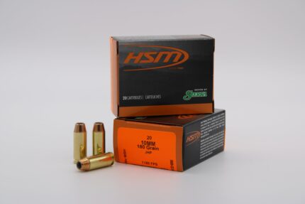 A box of HSM Ammunition 10mm Auto 180gr Jacketed Hollow Point ammunition next to several loose rounds displayed in front.
